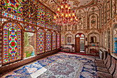 Interior view of the shahneshin (a dedicated reception room) with large colorful stained glass windows in Mollabashi Historical House in Isfahan, Iran.