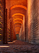 A low angle view through illuminated vaulted arches of the 17th century Khaju Bridge on Zayanderud river in Isfahan, Iran.