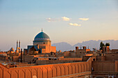 Rooftop view of the Seyed Rokn Addin Mausoleum (14th century) with its beautiful blue tiled dome lit by setting sun. Yazd, Iran.