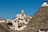 Trulli houses with the Church of Santa Lucia in the background in Alberobello, Puglia, Italy.