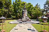 Large stone stupa and seated Buddha image in the garden of Mendut Buddhist Monastery. Magelang Regency, Java, Indonesia.