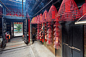 Burning incense spirals hang on rails in the Tin Hau Temple Complex. Yau Ma Tei, Kowloon, Hong Kong, China.