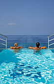  Woman and man relaxing on the edge of the infinity pool on the aft deck of the expedition cruise ship SH Diana (Swan Hellenic), at sea, near Saudi Arabia, Middle East 