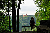 woman sitting on a bench overlooking the Gauja River with the Turaida Castle in background,around Sigulda,Gauja National park,Vidzeme Region,Latvia,Baltic region,Northern Europe