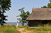 Woman walking on the coast beside  a fishermen hut,Altja,Baltic coast,Lahemaa National Park,estonia,northern europe