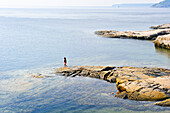 woman standing on rock at the confluence of Saguenay and Saint Lawrence rivers,Tadoussac,Cote-Nord region,Province of Quebec,Canada,North America