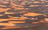  Camel driver with camels in the desert at sunset 