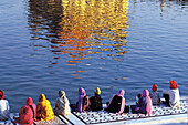 Pilgrims sitting near pond of golden temple, amritsar, punjab, india, asia