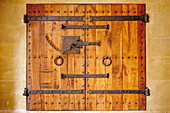 Close up view of an old wooden door with massive iron hinges in the Royal Abbey of Santa Maria de Poblet. Vimbodi i Poblet, Catalonia, Spain.