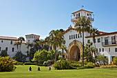 People sit on a manicured green lawn in front of the Santa Barbara County Courthouse. Santa Barbara, California, USA.