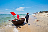 Vietnamese coracle fisherman on Cua Dai beach. Hoi An, Quang Nam Province, Vietnam.