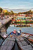 Vietnamese women sit on their boats moored together on Thu Bon River in Hoi An Ancient Town. Hoi An, Quang Nam Province, Vietnam.