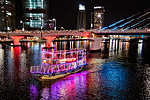 Tour boat moves along the Han River at night. Da Nang city, Vietnam.