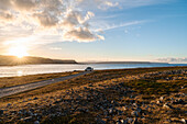 Norwegen, Finnmark, Varangerhalvøya, Hamningberg, Wohnmobil auf Küstenstraße mit Blick auf Meer am Abend