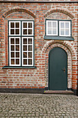  Green front door and lattice windows on brick facade 