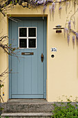  Old front door with wisteria on yellow facade 