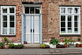  Grey-white old front door and lattice windows and plant pots on old house 