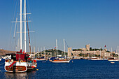 Traditional Turkish gulets anchored near the medieval Castle of The Knights of St.John (The Castle of St. Peter). Bodrum, Mugla province, Turkey.