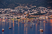 Boats anchored at sea in front of the coastal city of Bodrum at night. Bodrum, Mugla Province, Turkey.