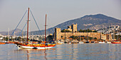 Turkish gulet anchored at sea near the medieval Castle of The Knights of St.John (The Castle of St. Peter). Bodrum, Mugla province, Turkey.