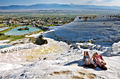 Two young girls sunbathe on travertine terraces of Pamukkale. Denizli Province, Turkey.