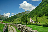  Path surrounded by stone walls and Holy Spirit Chapel in the background, Kasern, Ahrntal, Zillertal Alps, South Tyrol, Italy 