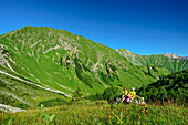  Man and woman hiking sitting on rocks and taking a break, Namloser Wetterspitze, Lechtal Alps, Tyrol, Austria 