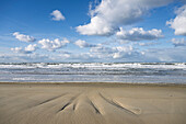 A serene beach scene with gentle waves and a cloudy sky.