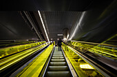 Banker in suit uses the yellow futuristic escalator in Canary Wharf metro station, Docklands, Tower Hamlets, Isle of Dogs, London, England, United Kingdom, UK, Europe