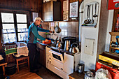  Man standing in front of the stove while cooking in the Loreahütte, Loreahütte, Lechtal Alps, Tyrol, Austria 