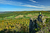  Man hiking sitting on twin rocks above the valley, Waberla, Kirchehrenbach, Franconian Switzerland, Franconia, Bavaria, Germany 