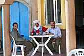 Three men sitting at sidewalk cafe at Tiznit, Anti-Atlas, Morocco, North Africa