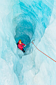 Mountaineer moving up ice cave, Fox Glacier, Westland National Park, South Island, New Zealand