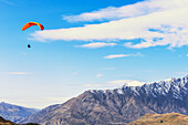  Paragliding über der schneebedeckten Remarkables-Bergkette, Queenstown, Südinsel, Neuseeland 
