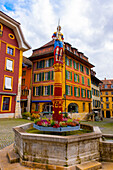 Square in Old Town with House and Water Fountain with Statue and Sky with Clouds in a Sunny Autumn Day in City of Biel, Bienne, Bern Canton, Switzerland.