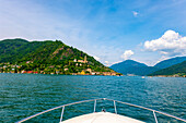 View From a Motorboat on Lake Lugano and House and Church on Mountain Range in a Sunny Summer Day on the Waterfront in Morcote, Lugano, Ticino, Switzerland.