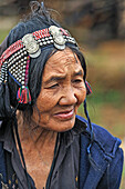 Woman from Akha Puli tribe wearing a headdress decorated with old French Indo-China silver coins, living in village in the mountains surrounding Muang La, Oudomxay Province in northwestern Laos, Southeast Asia