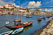 Traditional Portuguese wooden cargo boats transporting port wine, Rio Douro river, Vila Nova de Gaia, Ponte Dom Luis I bridge, Porto, Portugal