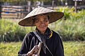 Ältere einheimische Frau mit konischem Hut auf der Laos Buffalo Dairy Farm, bei Kuang Si, Luang Prabang District,  Laos, Asien