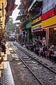  A passenger train approaches while tourists sit in cafes near the railway tracks on the famous &quot;Train Street&quot; in Hanoi&#39;s Old Quarter, Hanoi, Hanoi Capital, Vietnam, Asia 