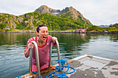 Young woman, dressed with an old-fashioned swimming costume, bathing into the icy water of the fjord.Hamn i Senja Hotel.Senja island.County of Troms,Norway,Northern Europe