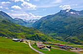 Berggipfel mit Gletscher und Bahnhof mit Glacier-Express-Zug im Tal in Andermatt, Uri, Schweiz.