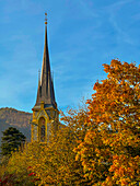 Church Tower and Beautiful Autumn Tree and Mountain with Blue Sky in a Sunny Day in Bad Ragaz, St Gallen, Switzerland.