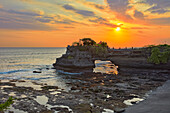 Batu Bolong Temple (Pura Batu Bolong), a Hindu temple built on a large rock with a hole in the middle, at sunset. Tanah Lot, Bali, Indonesia.