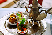 Pfefferminztee arabischer Art mit vier Stücken Hlou, tunesischer Patisserie, serviert auf Silbertablett mit Silberkanne in tunesischem Café in Hammamet , Tunesien