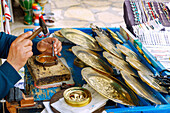  Craftsmen working on brass plates with carved scenes and figures at the market in the Medina in Hammamet, Tunisia 