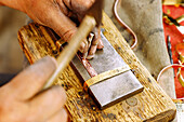  Craftsman engraving a copper bracelet with a traditional engraving tool in the souk in the Medina of Nabeul, Tunisia 