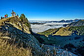  Two people hiking past a mountain chapel with a sea of fog in the valley, Brecherspitze, Spitzing, Bavarian Alps, Upper Bavaria, Bavaria, Germany 