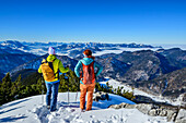 Mann und Frau beim Winterwandern blicken auf Kaisergebirge und Chiemgauer Alpen, vom Dürrnbachhorn, Reit im Winkl, Chiemgauer Alpen, Oberbayern, Bayern, Deutschland