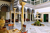  Courtyard decorated with tiles and colorful columned arcades in the historic Dar Bach Hamba Palace in the Medina of Tunis, Tunisia 